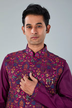Man wearing a purple traditional outfit with a floral pattern on a gray background
